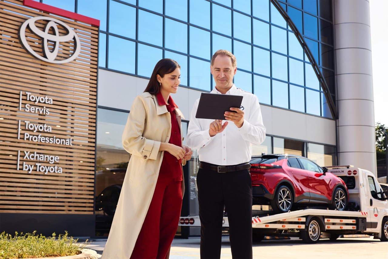 müşteriyle tablet üzerinden araç bakım süreci hakkında bilgi paylaşırken gülümseyerek hizmet veren Toyota servis danışmanı